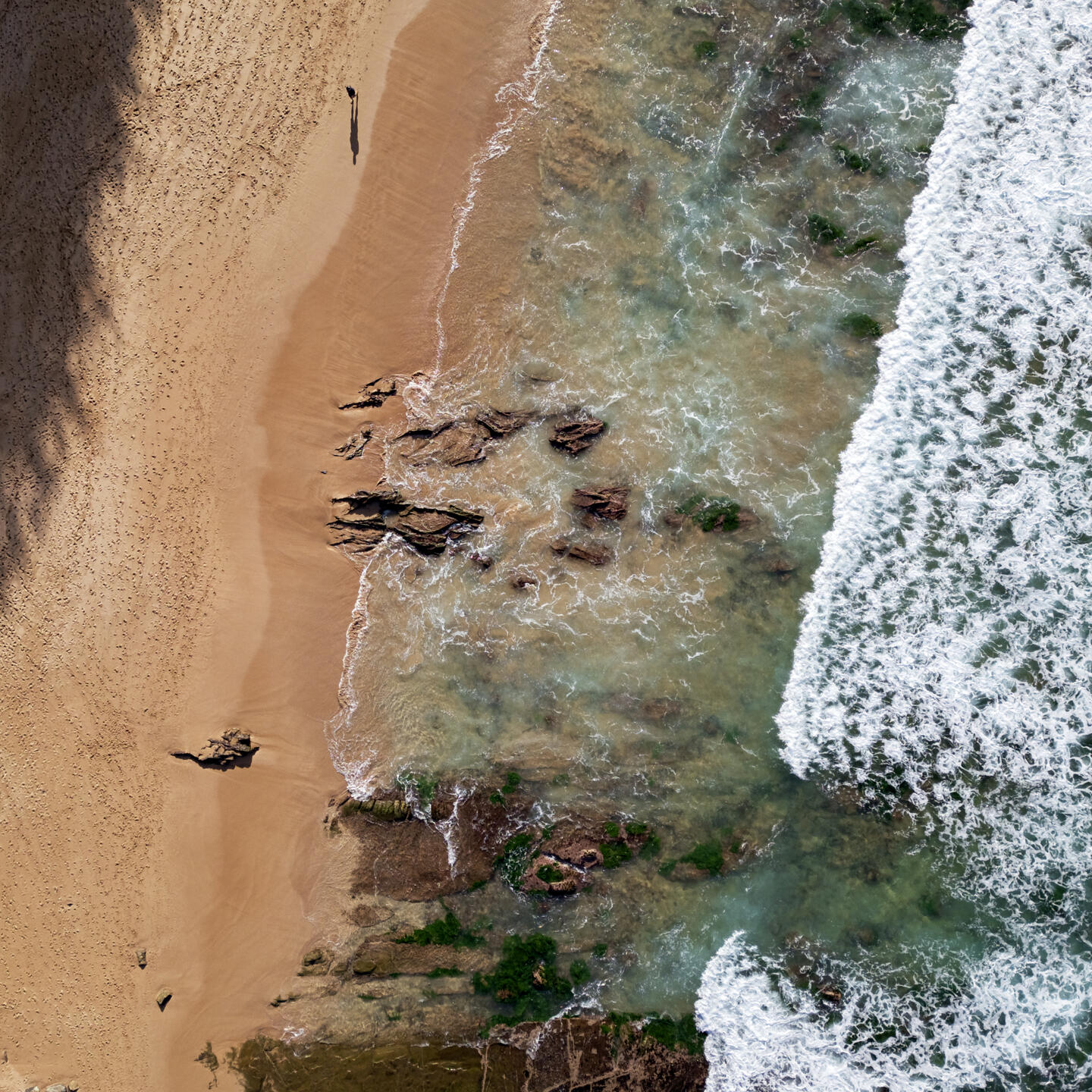 a drone photo of waves coming in to a beach